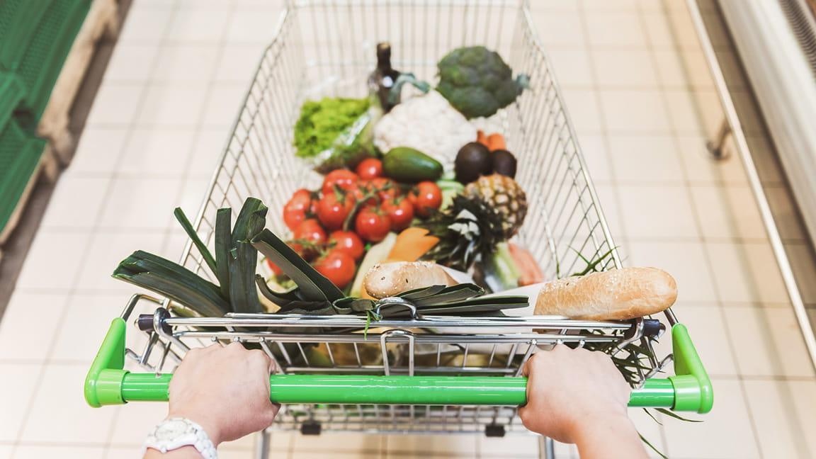 hands pushing grocery cart down isle in store