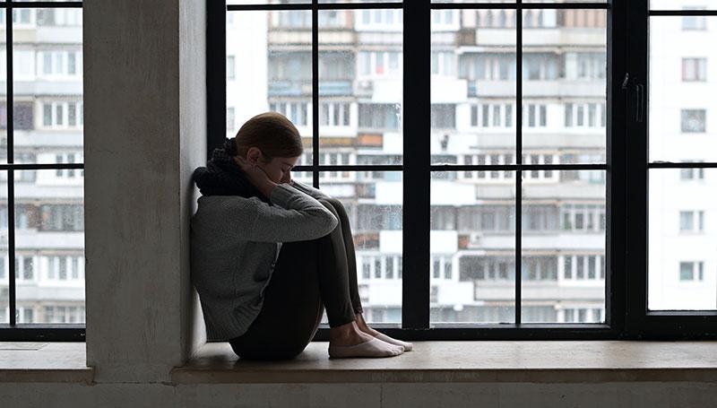 sad woman in windowsill